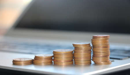 Stacks of coins reminding dgrowing diagram on computer keyboard. Business growth and expanding...