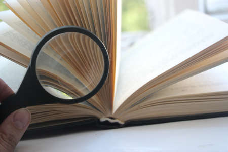 open book with magnifying glass over nature background. Searching information, power of knowledge...
