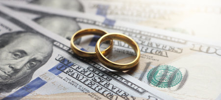 Wedding rings on the background of 100 dollars bills. Marriage conctract or prenuptial agreement concept