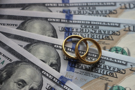 Wedding rings on the background of 100 dollars bills. Marriage conctract or prenuptial agreement conceptの写真素材
