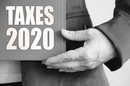 Taxes 2020 words on the cover of folder n businesswoman hands. business conceptの写真素材