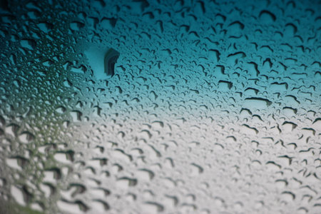 Blue water drops on ocean blue to silver gray gradient background.の写真素材