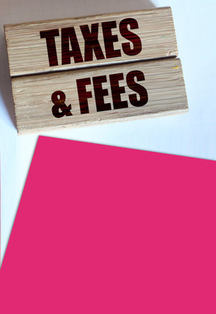 Taxes and fees Text on the wooden blocks, magenta pink paper. Business concept.の写真素材