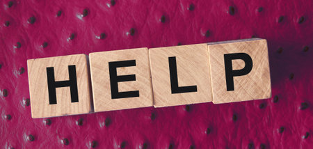 Word HELP is written on wooden blocks. Blocks are located on a wine red leather. Support desk, education or business concept.の写真素材