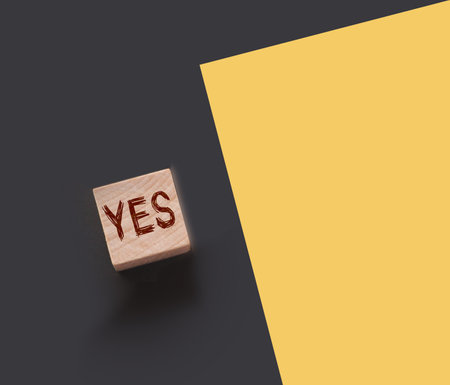 Word YES on wooden block and yellow paper besides. Business and career, education choice concept.の写真素材