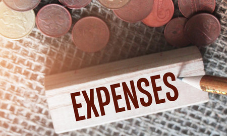 Expences word on wooden block and coins on burlap. Costs and expendditure in business financial concept.の写真素材