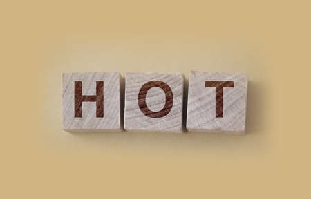 HOT word written on wooden blocks and placed on a yellow. Vacancy, sale and hot seat concept.の写真素材