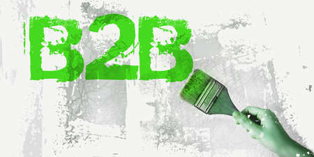 B2B abbreviation in Red and brush in hand on grundge white gray background. Business to Business Concept image.の写真素材