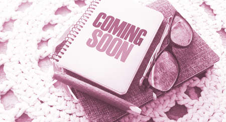 Coming soon on the cover of copybook, glasses and pen on crochet carpet. Business and education program concept.の写真素材