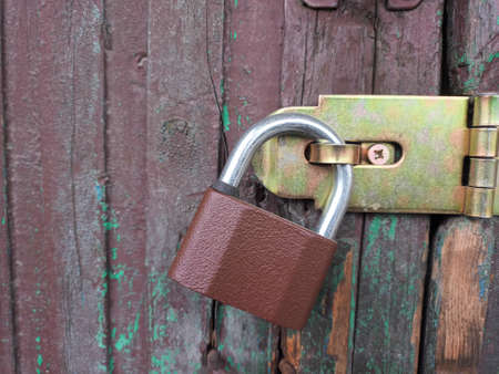 Hanging padlock on locked old wooden door.の写真素材