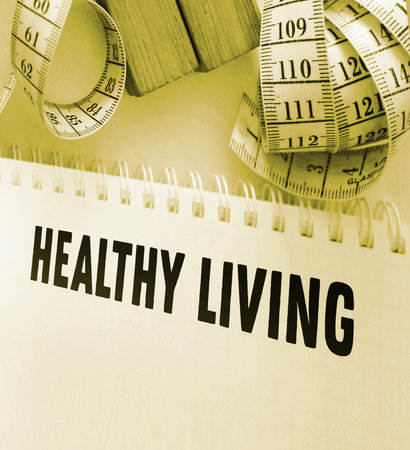 A white measuring tape and copybook with Healthy living words. Healthcare and fitness concept.の写真素材