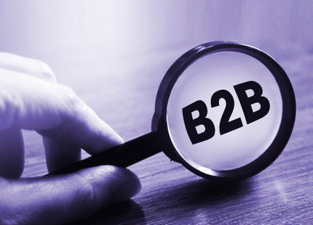 Businessman holding a magnifying glass abbreviation B2B. Business to Business concept.の写真素材