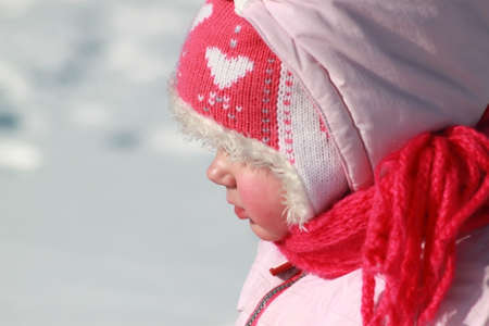 Girl playing in the snow A child in a pink hat in winterの写真素材