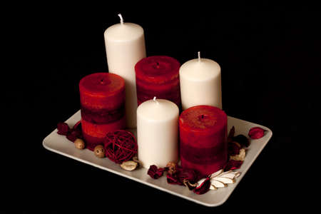 Cream and red candles with red potpourri on a black backgroundの写真素材