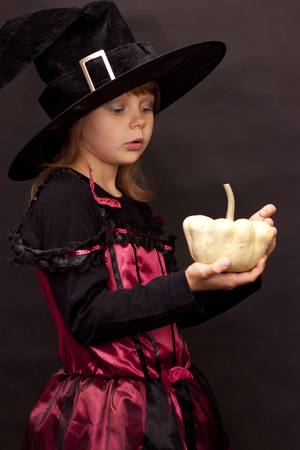 Girl in disguise for Halloween with pumpkin in her handsの写真素材
