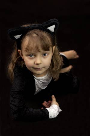 Girl dressed as a cat lying on black backgroundの写真素材