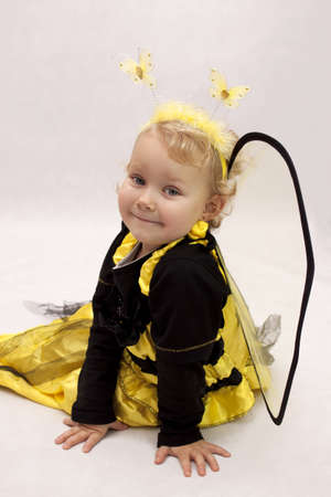 Child dressed as a bee sitting on white backgroundの写真素材