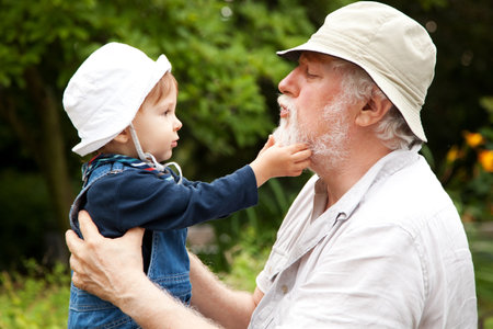 Grandchild and grandfather having fun outdoors.の写真素材