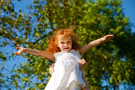 Adorable 3 year old girl playing aeroplane outdoorsの写真素材