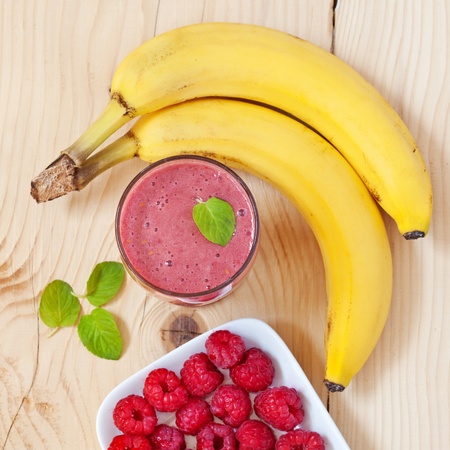A glass of raspberry smoothie with fresh raspberries, mint leaves and bananaの写真素材