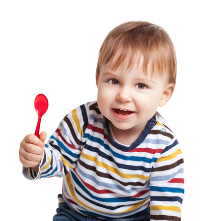 Adorable one year old child holding spoon and smiling, isolated on whiteの写真素材
