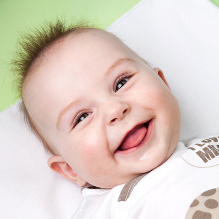 Close up of adorable 6 months old baby laughing and sticking out its tongueの写真素材