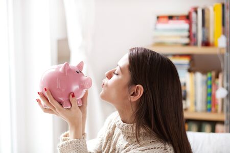 Woman kissing piggy bankの写真素材
