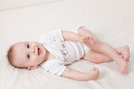 Adorable baby boy on his back playing and laughingの写真素材