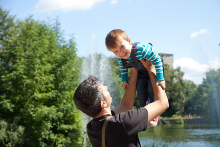 Father picking up smiling toddler in the parkの写真素材