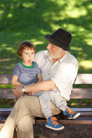 Grandfather having great fun with his grandson in the parkの写真素材