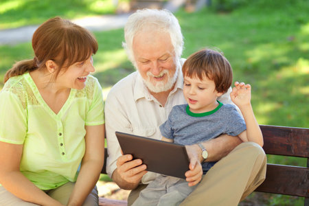 Grandson and grandparents using tablet in the park, shallow depth of field
