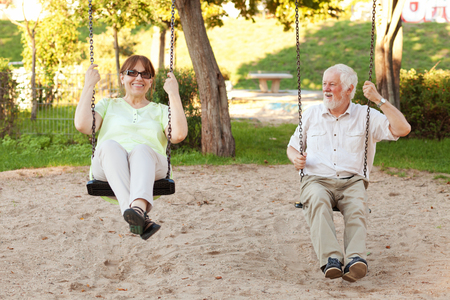 Senior couple having fun on park swingsの写真素材
