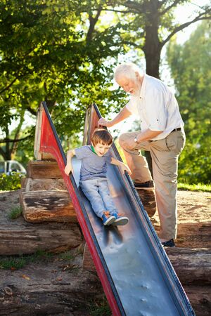 Grandson and grandfather having fun at the playgroundの写真素材
