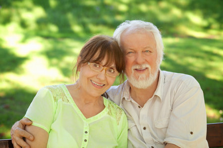 Senior couple sitting on a park bench hugged, shallow depth of field