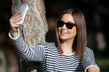 Beautiful young woman taking self portrait outdoorの写真素材