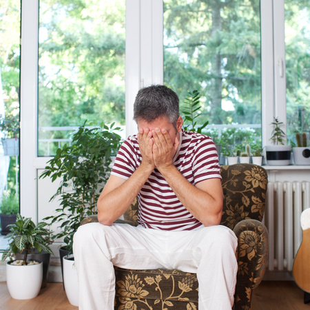 Portrait of depressed young man sitting in armchairの写真素材