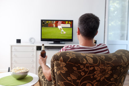 Image of a young man watching sports on TVの写真素材