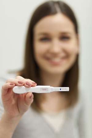 Young woman holding pregnancy test, shallow depth of fieldの写真素材