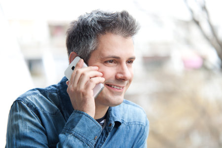 Young man using cell phone outdoors, shallow depth of field