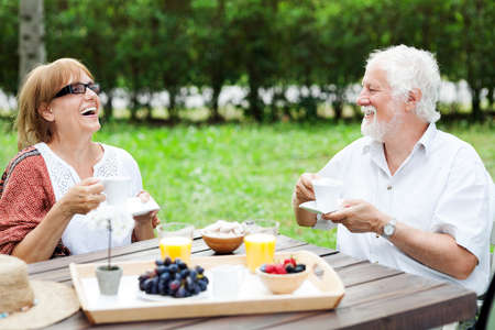Senior couple enjoying a cup of coffee in the garden, shallow depth of fieldの写真素材