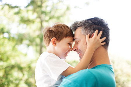 Father and son hugging outdoors, shallow depth of field