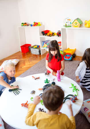 A group of children playing with animal toys in kindergartenの写真素材