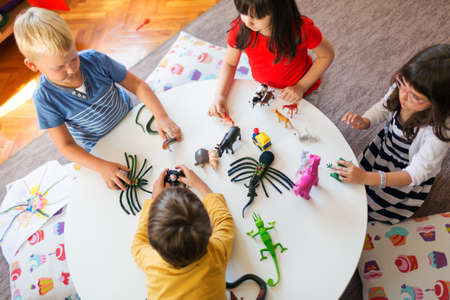 A group of children playing with animal toys in kindergartenの写真素材