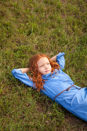 Beautiful ginger girl lying on grassの写真素材