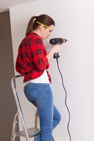 Beautiful young woman using a drillの写真素材