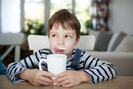 Adorable boy drinking milk or yogurt, shallow depth of fieldの写真素材
