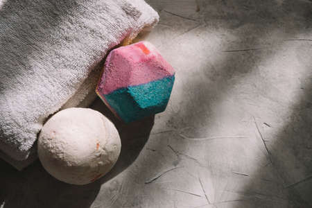 Top view of two bath bombs placed next to a white towel on a gray surface with soft light. Self care concept.の写真素材