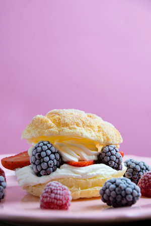 Vertical photography of puff pastry filled with whipped cream, raspberries, blackberries and...