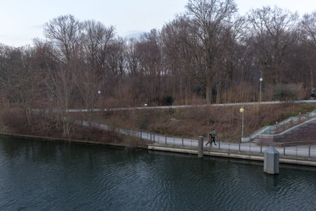 River in Tiergarten, showing water, grass, trees and a couple walking.