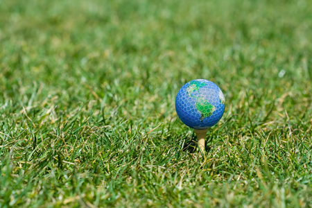 Single earth golf ball lying on green grassの写真素材